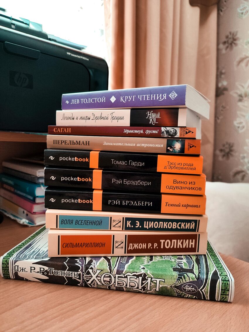 A stack of various books in different languages on a wooden table, ideal for education themes.